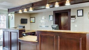A reception desk with a wooden finish, a sign reading "QUALITY INN BY CHOICE HOTELS," and a framed certificate on the wall. - Quality Inn Shreveport Airport (Shreveport)