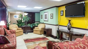 A living room with a sofa set, armchairs, a coffee table, a TV mounted on the wall, and a potted plant. - Quality Inn Shreveport Airport (Shreveport)