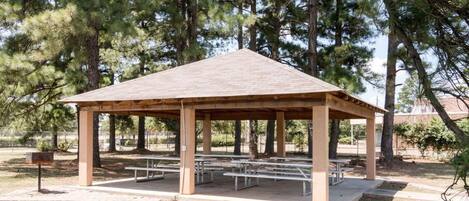 A gazebo with picnic tables in a park.
