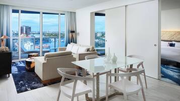 Habitación de hotel moderna con un balcón grande, un área de comedor y vistas de la ciudad.