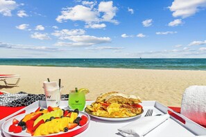 A beachside table with a meal, a drink, and a towel.