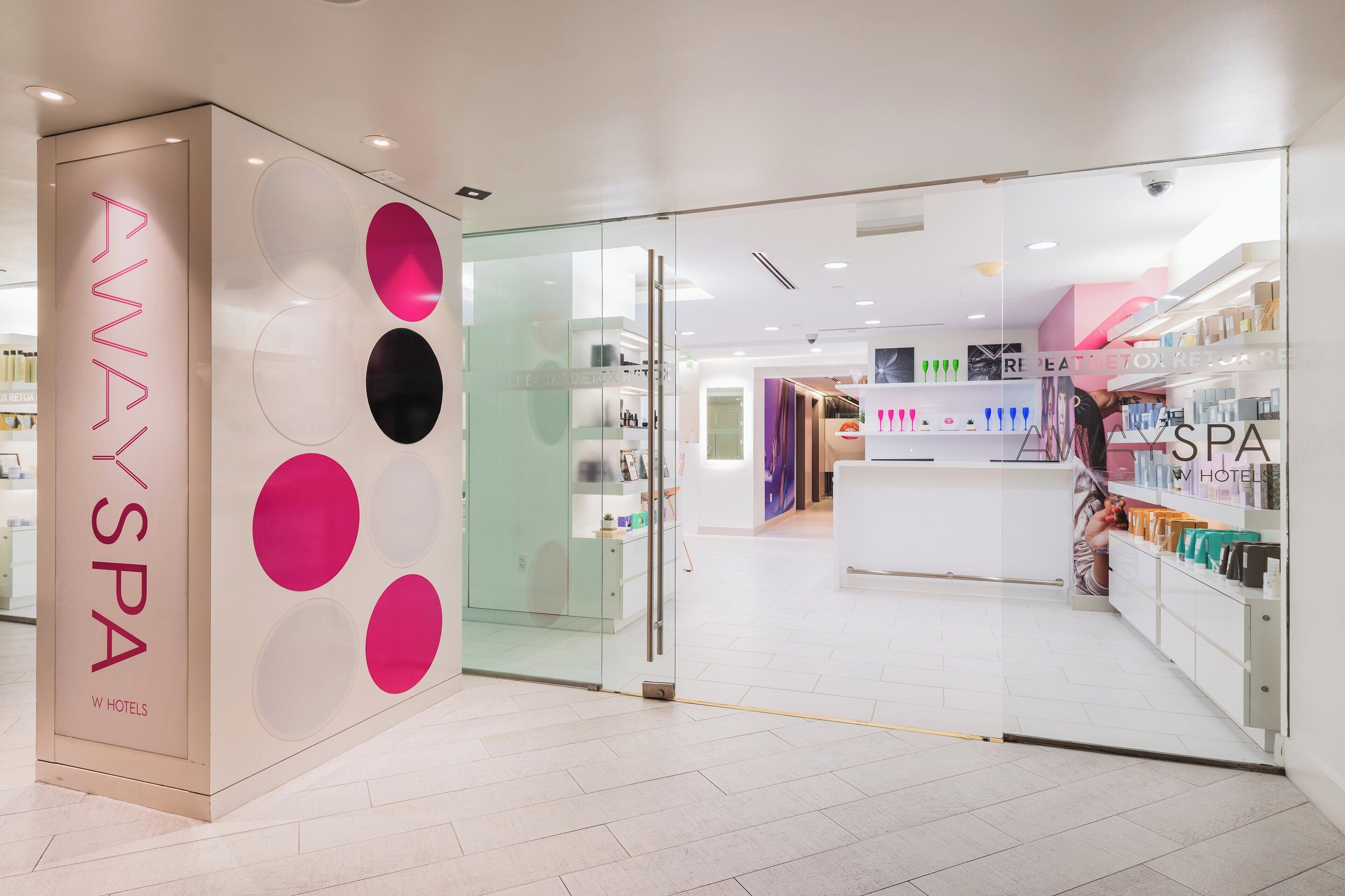 Een moderne spa met glazen entree, een zichtbaar receptiegedeelte en diverse spa-producten in etalage.