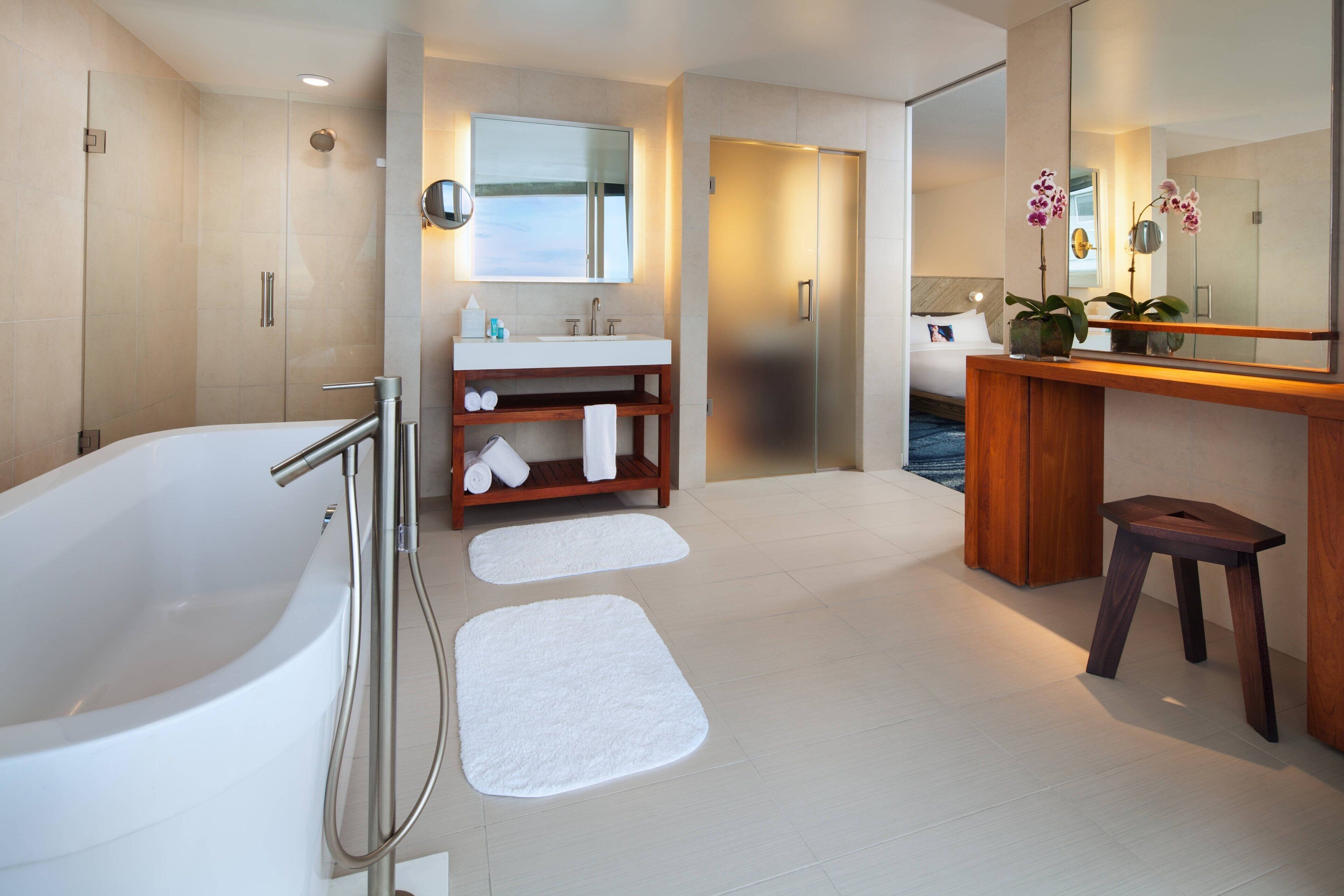 A modern bathroom with a large bathtub, a vanity with a mirror, and a shower area.