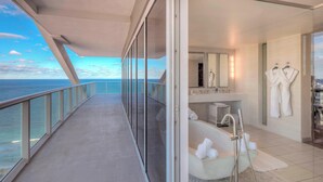 A modern hotel room with a balcony overlooking the sea, a bathtub, and a vanity with a mirror and towel rack. - W Fort Lauderdale (Fort Lauderdale)