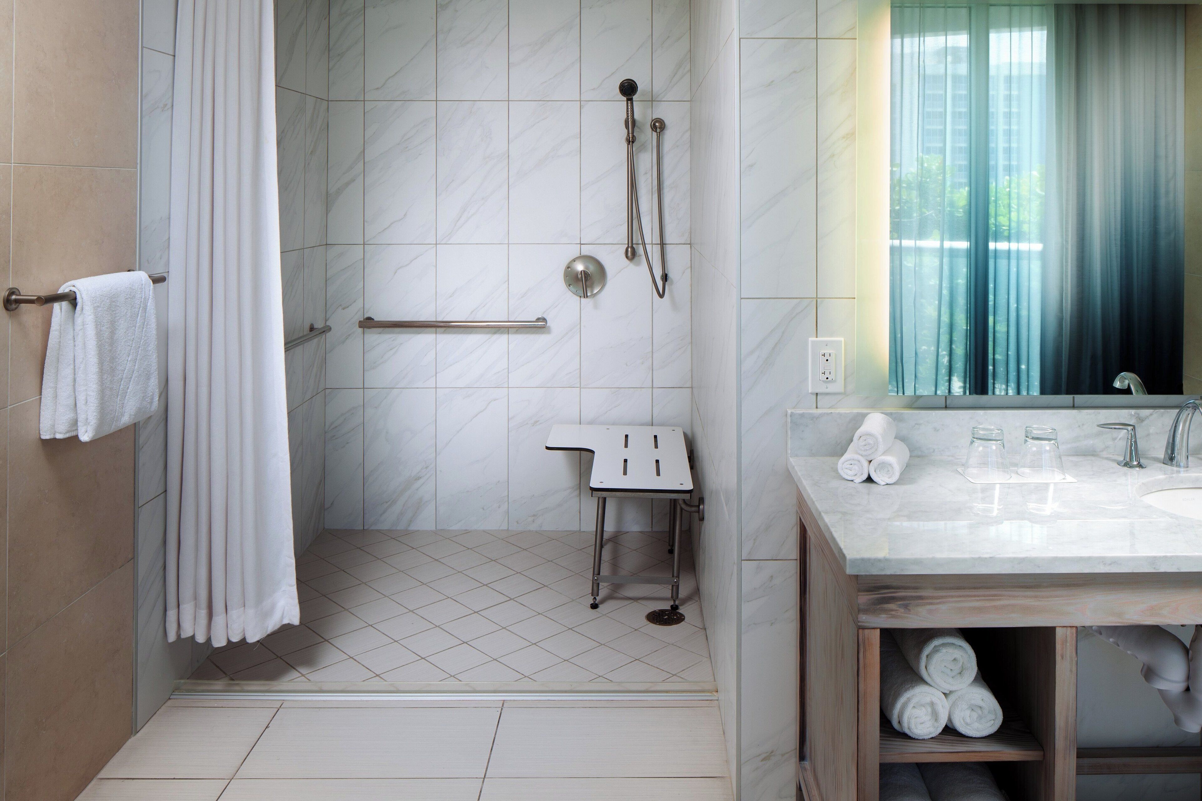 A bathroom with a shower, a sink, and a mirror.