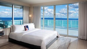 A spacious bedroom with a large bed, a nightstand, and a view of the ocean through large windows. - W Fort Lauderdale (Fort Lauderdale)