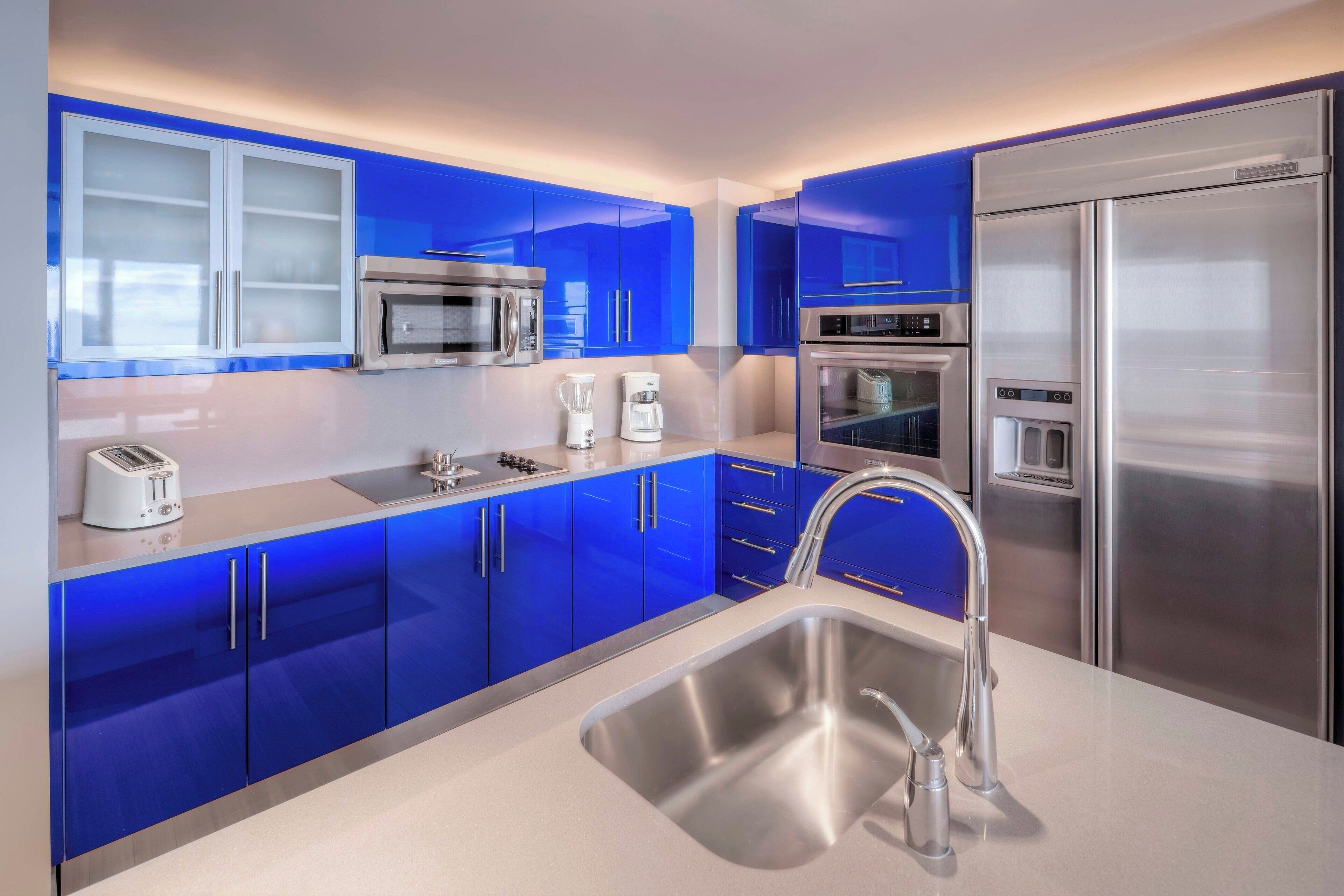 Una cocina moderna con armarios azules, electrodomésticos de acero inoxidable y una isla central con pileta.