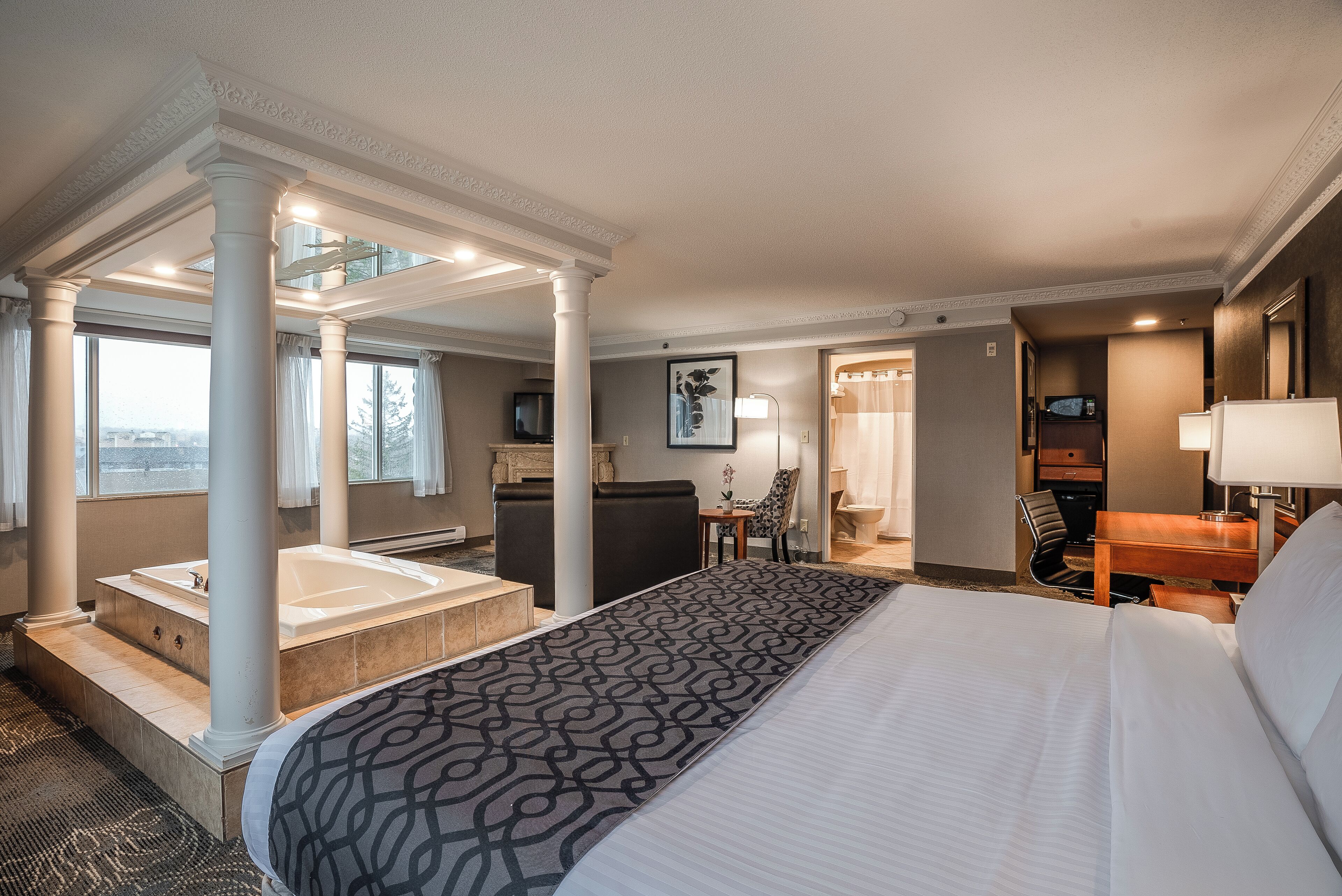 Habitación de hotel con una cama grande, baño independiente con bañera, escritorio y una silla.