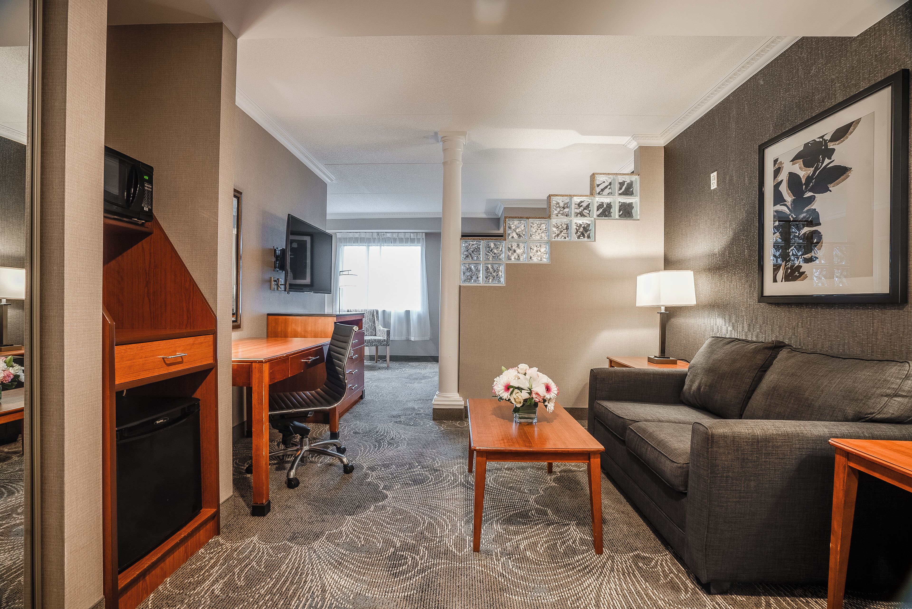 Ein Hotelzimmer mit Küchenzeile, einer Sitzecke, einem Schreibtisch und einem Couchtisch.