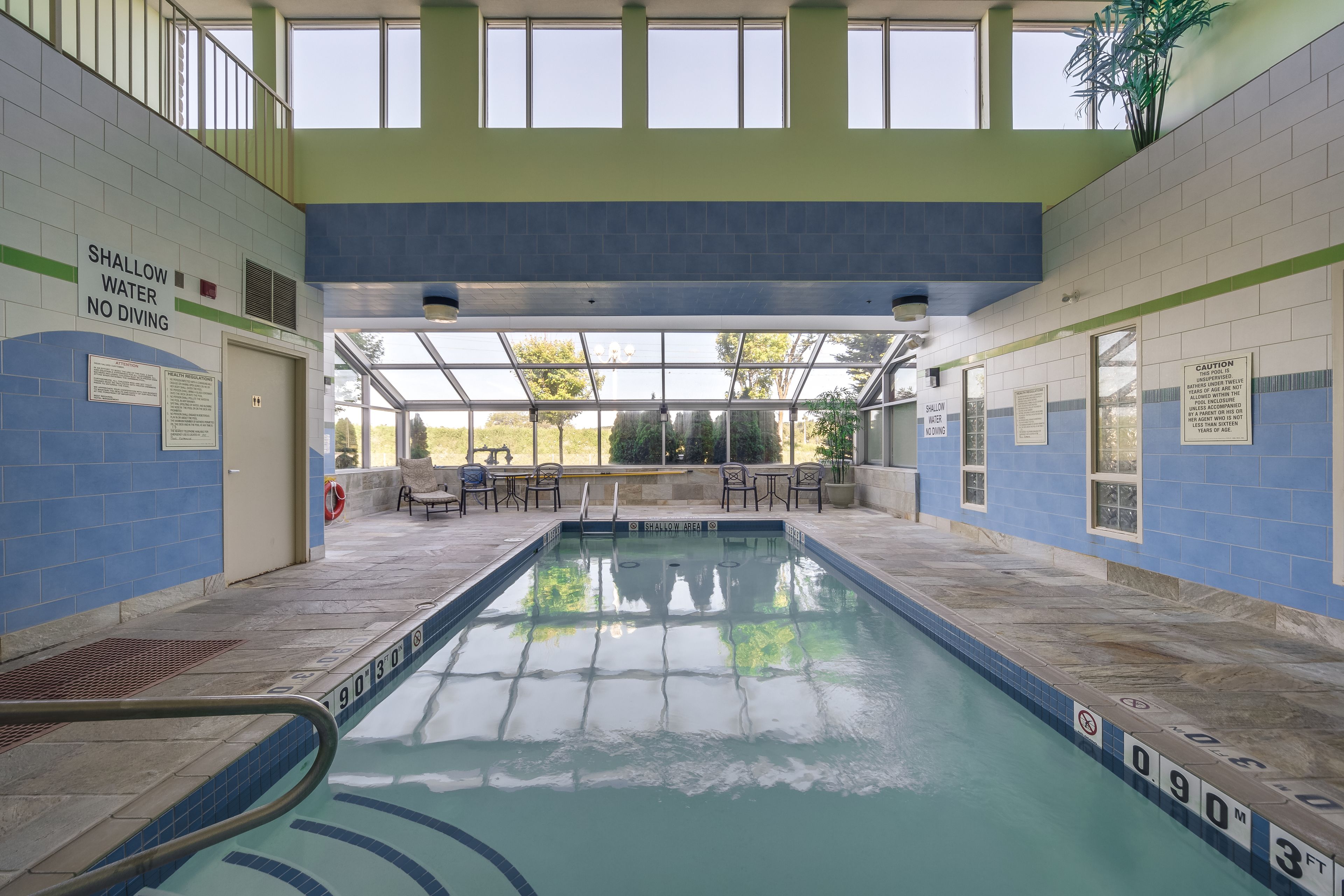 An indoor swimming pool with clear signage indicating shallow water and no diving.
