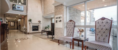 A spacious lobby with a fireplace, comfortable seating, and a large window offering a view of the outside.
