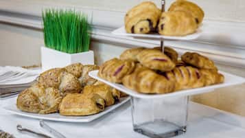 A buffet table with various pastries and a small potted plant.