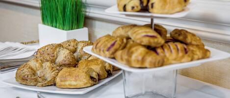 A buffet table with various pastries and a small potted plant.