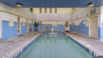 Una piscina interior con paredes de azulejos, un cartel de poca profundidad y un cartel de prohibido bucear.