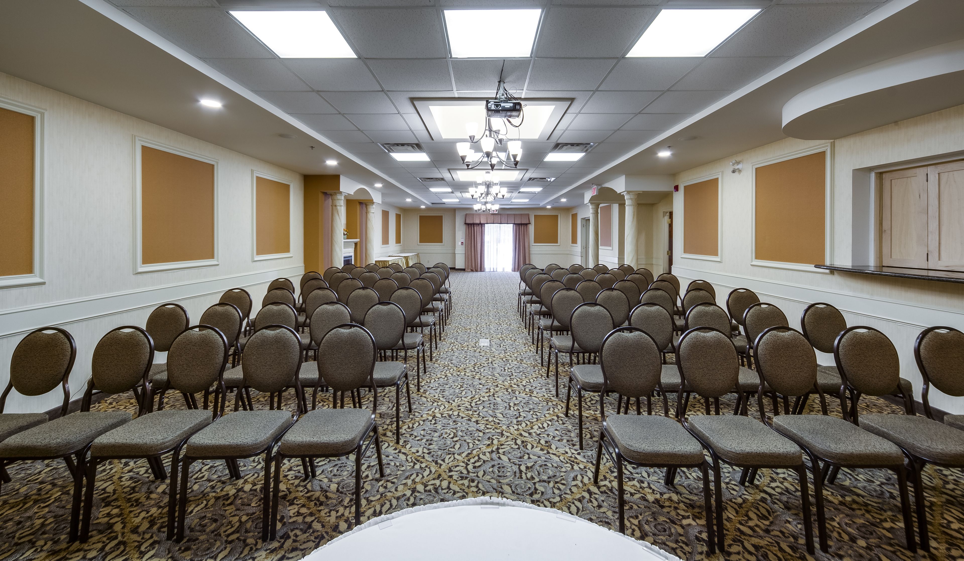 Una sala conferenze con file di sedie, un proiettore e un pavimento rivestito di moquette.