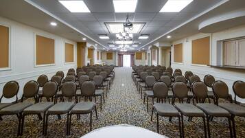 Una sala conferenze con file di sedie, un proiettore e un pavimento rivestito di moquette.