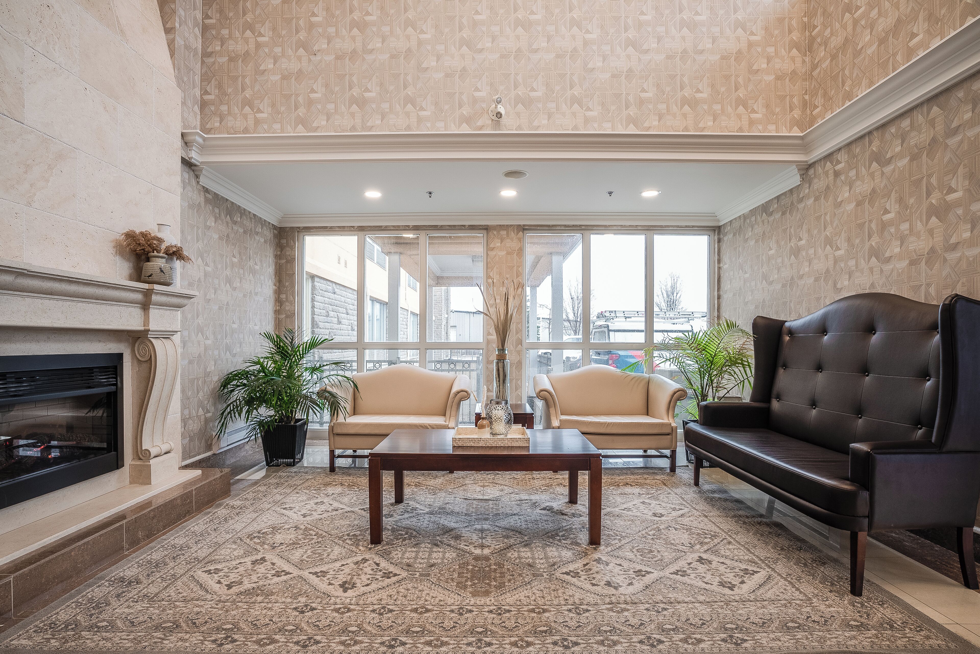 Amplia sala de estar con chimenea, dos sofás, una mesa de centro y grandes ventanales con vistas a la ciudad.