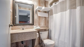 Un baño con encimera de granito, inodoro, toallero y cortina de ducha.