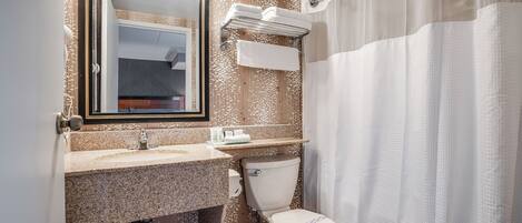 A bathroom with a granite countertop, a toilet, a towel rack, and a shower curtain.