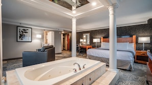 Una habitación de hotel moderna con una bañera grande, una cama, un escritorio y una silla.