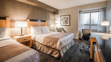 A hotel room with two beds, a desk, a chair, and a window with curtains.
