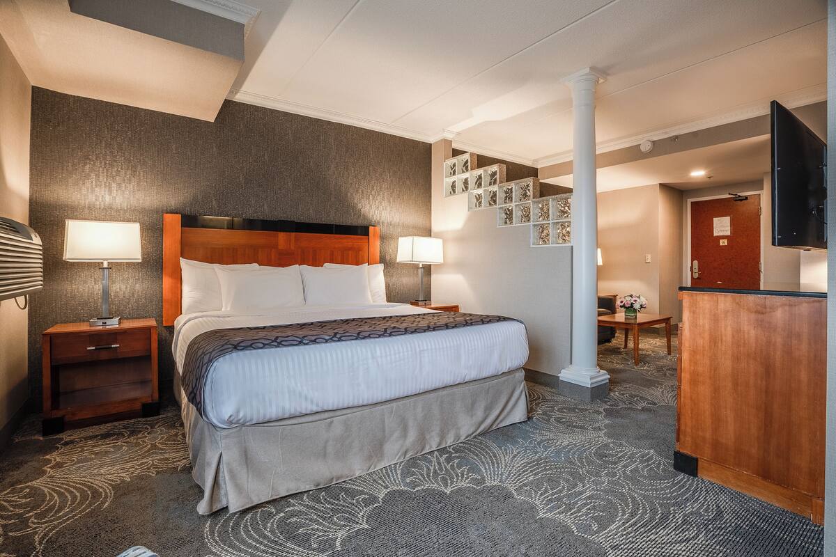 A hotel room with a large bed, two bedside tables, a desk, and a TV.