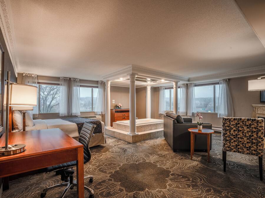 Una habitación de hotel con cama, escritorio, silla y un pequeño rincón de descanso.