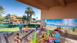 Children playing in a sandpit with water slides in the background. - Sahara Beach Aquapark (Monastir)