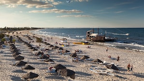 A beach with umbrellas, lounge chairs, and a lifeguard tower. - Sahara Beach Aquapark (Monastir)
