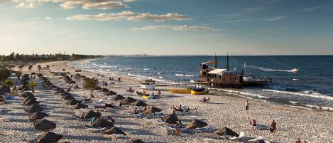 A beach with umbrellas, lounge chairs, and a lifeguard tower.