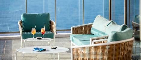 A balcony with wicker furniture, two drinks, and a magazine on a table.