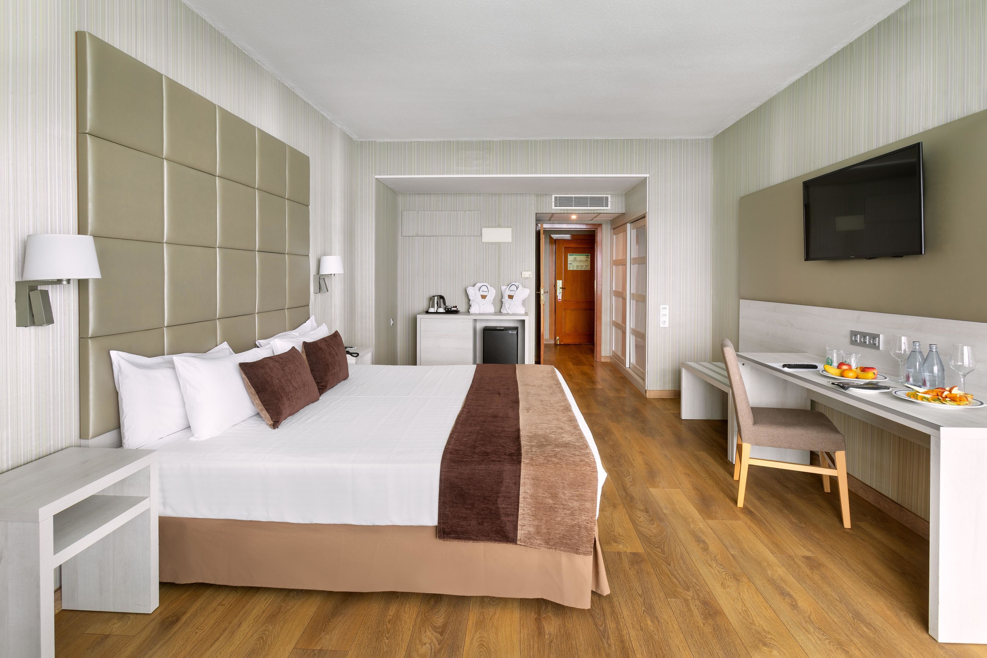 Une chambre d’hôtel avec un grand lit, un bureau et une télévision.
