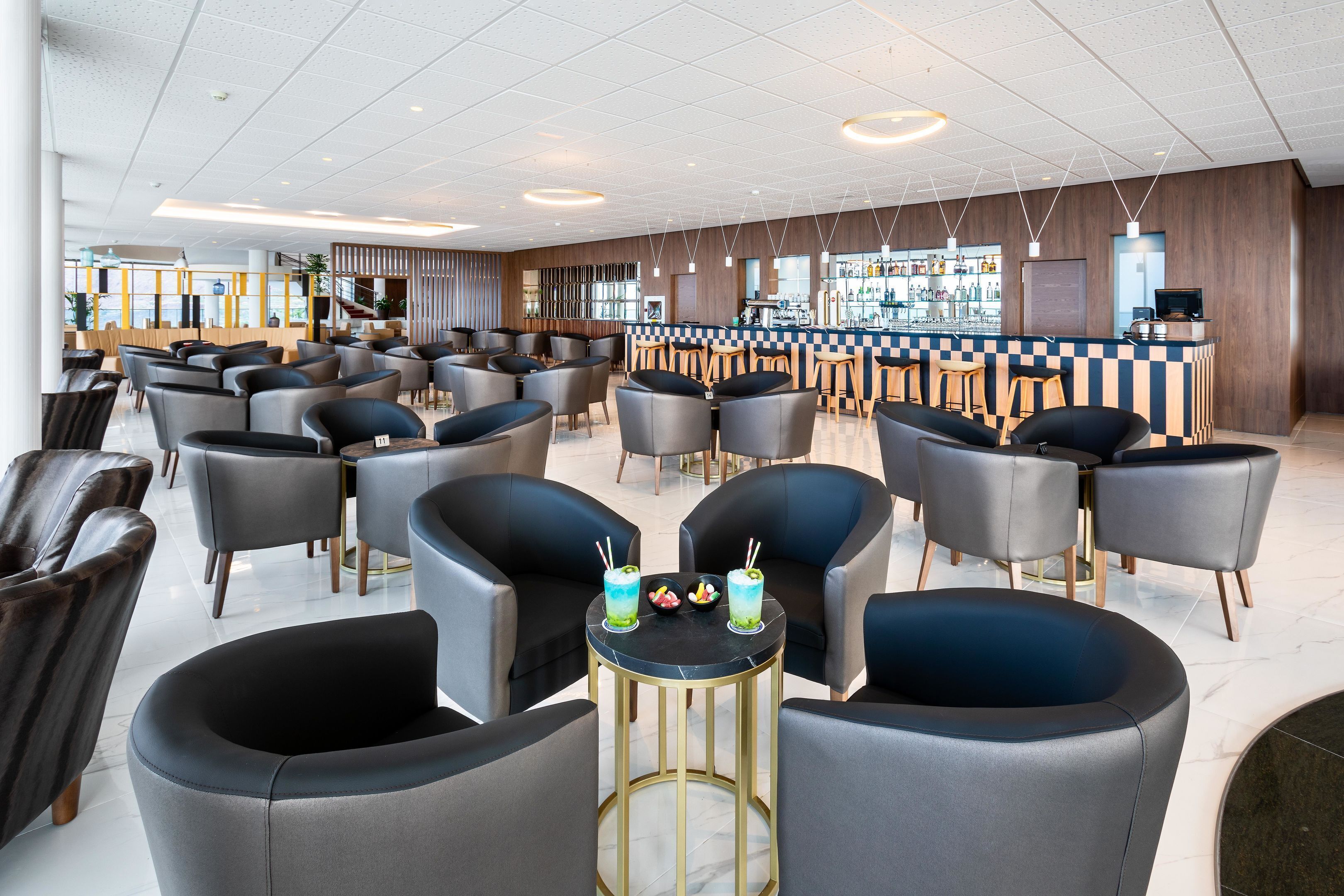 Een moderne bar met een schaakbordvloer, verschillende zithoeken en een barista-werkstation.