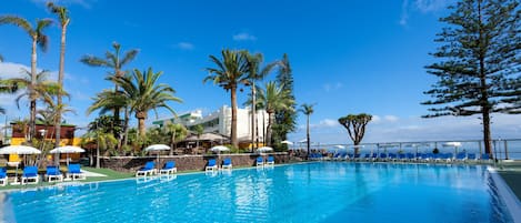 Una piscina techada, una piscina al aire libre, sombrillas