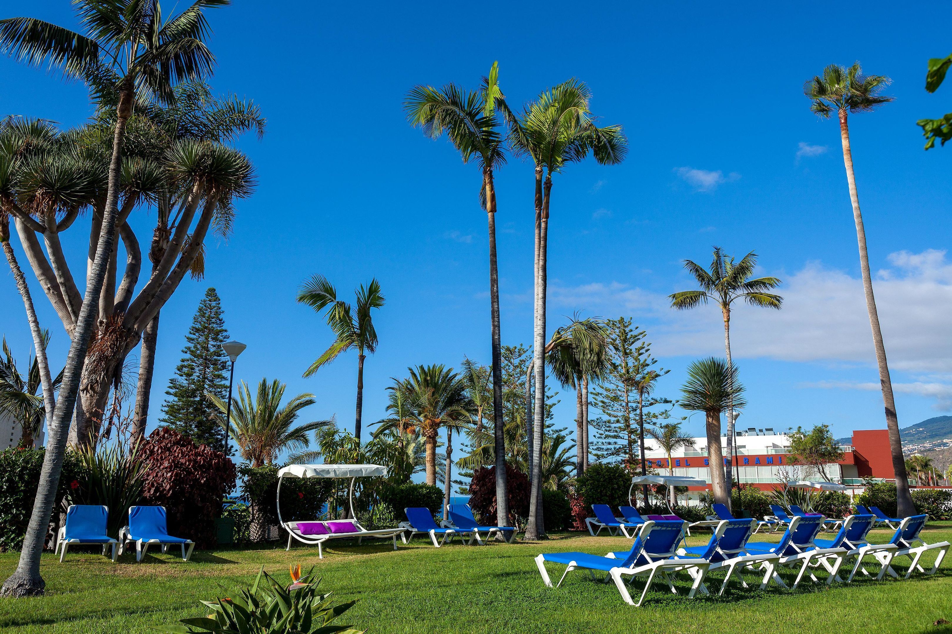 A resort with a pool area, palm trees, and lounge chairs.