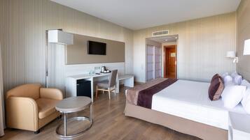 A hotel room with a bed, a desk, a chair, and a small round table.