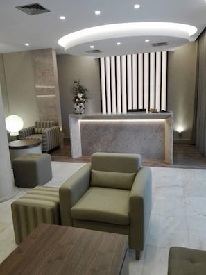 Un espace d’accueil moderne avec un comptoir en marbre, des sièges confortables et une plante décorative.