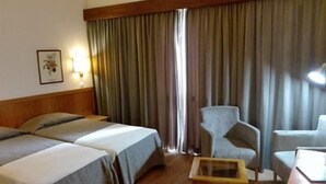 A hotel room with two beds, a small table, and a chair. - Hotel Do Centro (Funchal)
