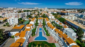 A resort with a central pool, multiple buildings with orange roofs, and a view of the surrounding city. - Apartamentos Turísticos Club Ouratlântico (Albufeira)