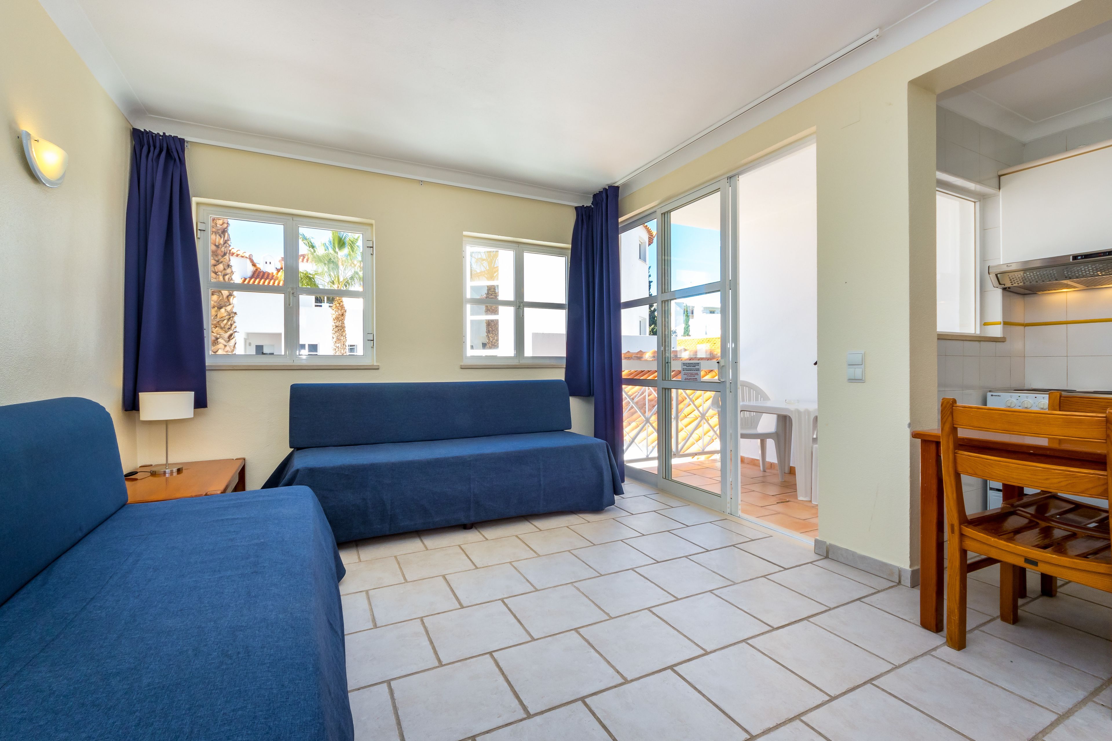 Ein Zimmer mit einer Couch, einem Tisch und Blick ins Freie.