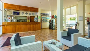 A hotel lobby with a reception desk, seating area, and a view of the outside. - Apartamentos Turísticos Club Ouratlântico (Albufeira)