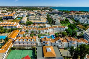 A coastal resort area with multiple buildings, a swimming pool, and a tennis court.