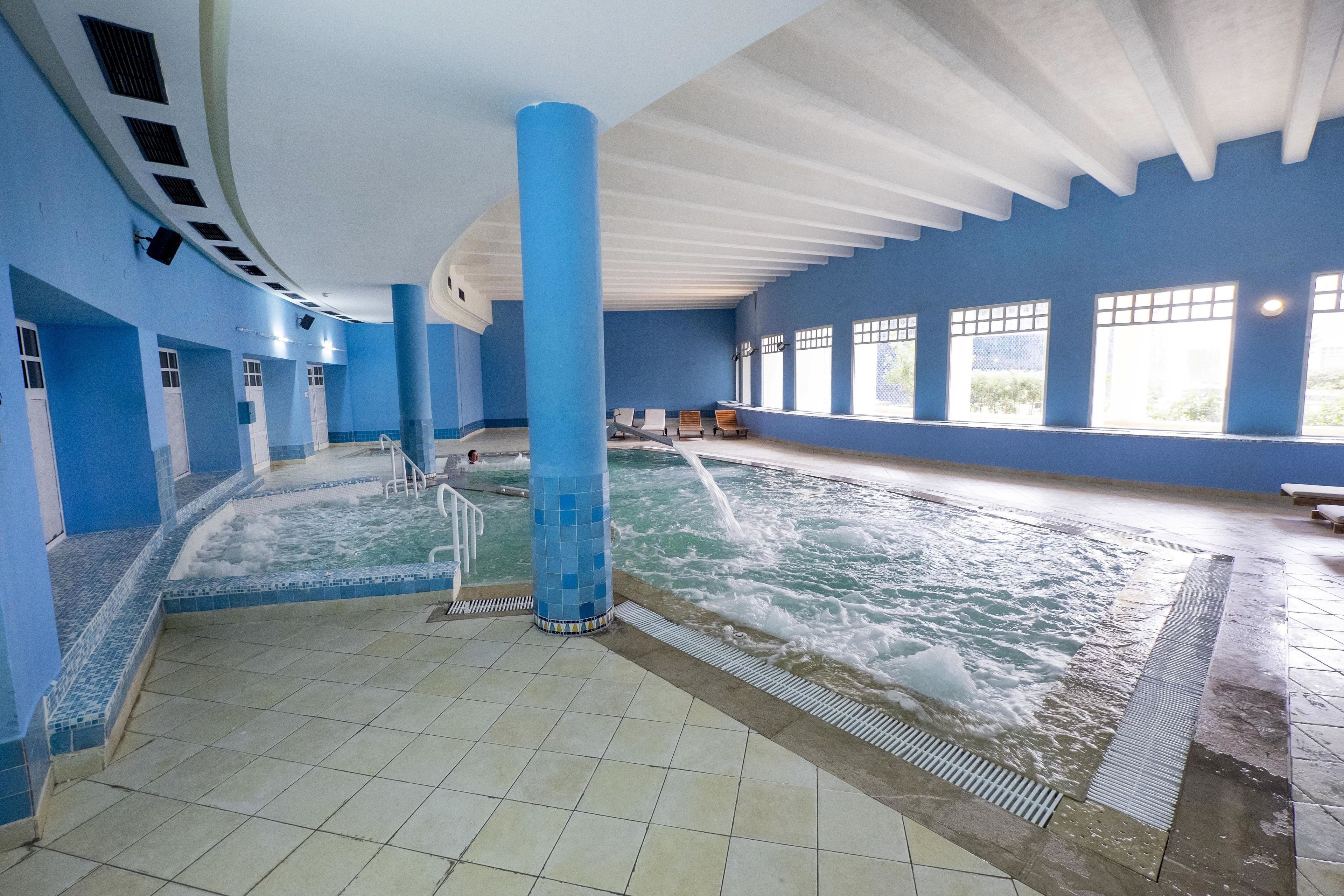 An indoor swimming pool with blue walls and a tiled floor.