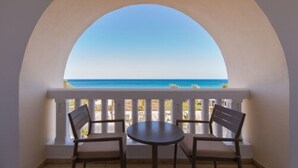 A balcony with two chairs and a table, overlooking a beach. - Medina Solaria & Thalasso (Hammamet)