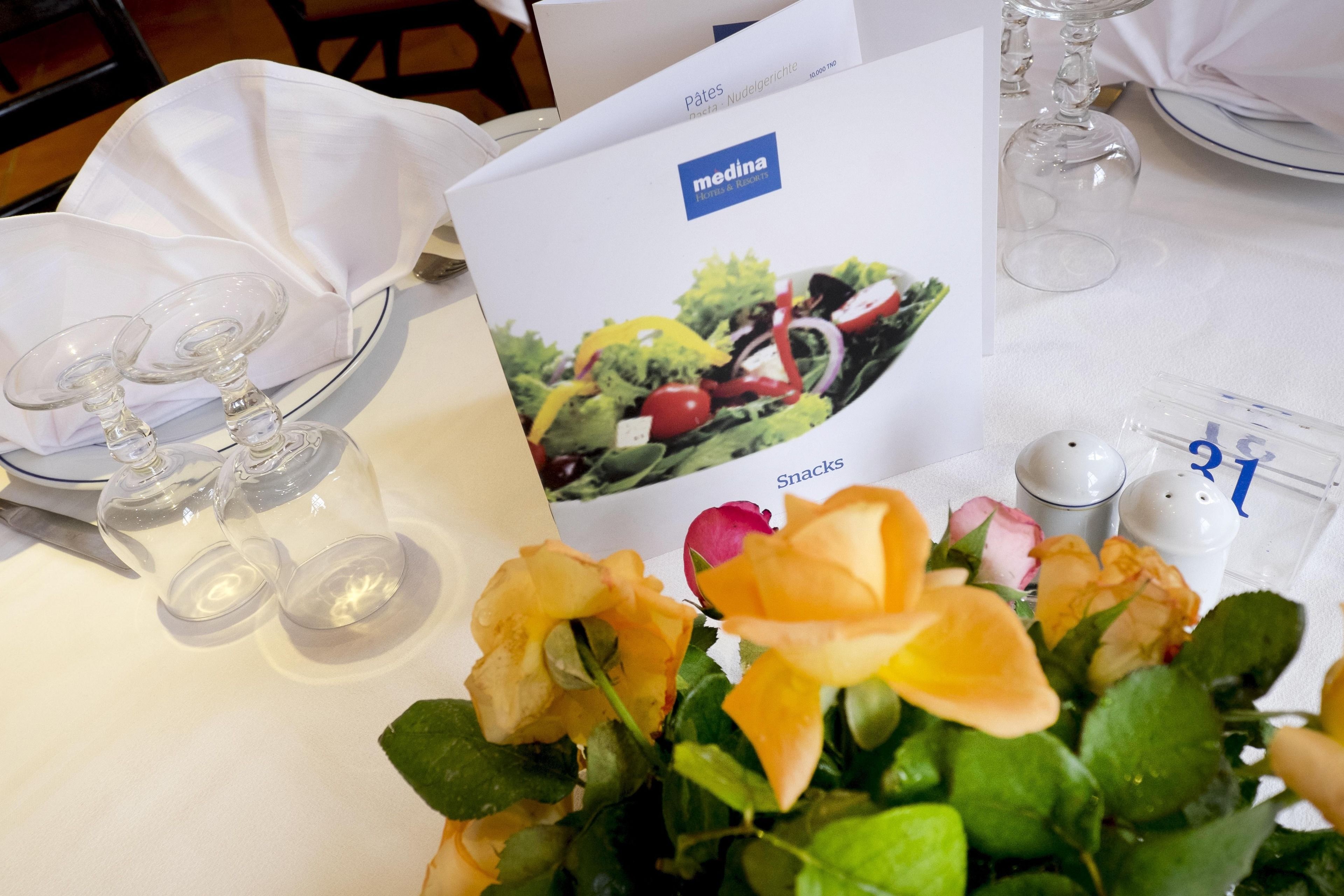 A table set with a menu, wine glasses, and a flower arrangement.