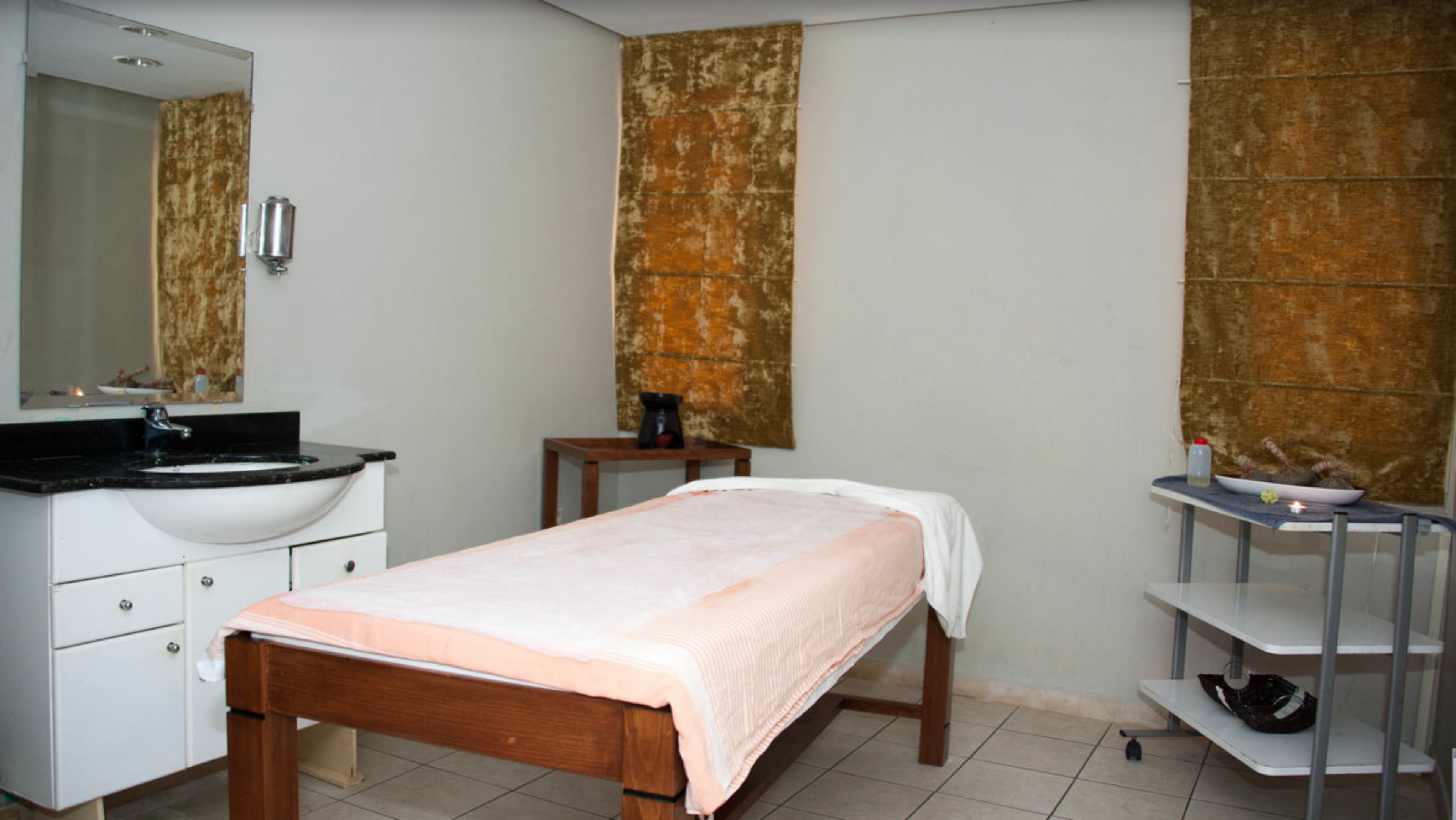 Une chambre à coucher comprenant un lit, une table de chevet, une petite table avec une machine à café, un miroir et une étagère avec un bol.