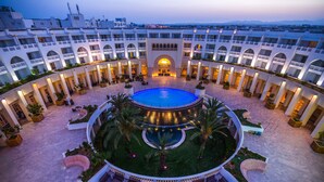 A hotel courtyard with a central pool, multiple balconies, and outdoor seating areas. - Medina Solaria & Thalasso (Hammamet)