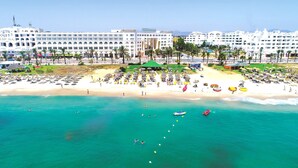 A beach resort with a large hotel, sun loungers, umbrellas, and clear turquoise waters. - Medina Solaria & Thalasso (Hammamet)
