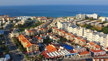 A coastal town with a mix of residential and commercial buildings, including hotels with red-tiled roofs and visible signage.