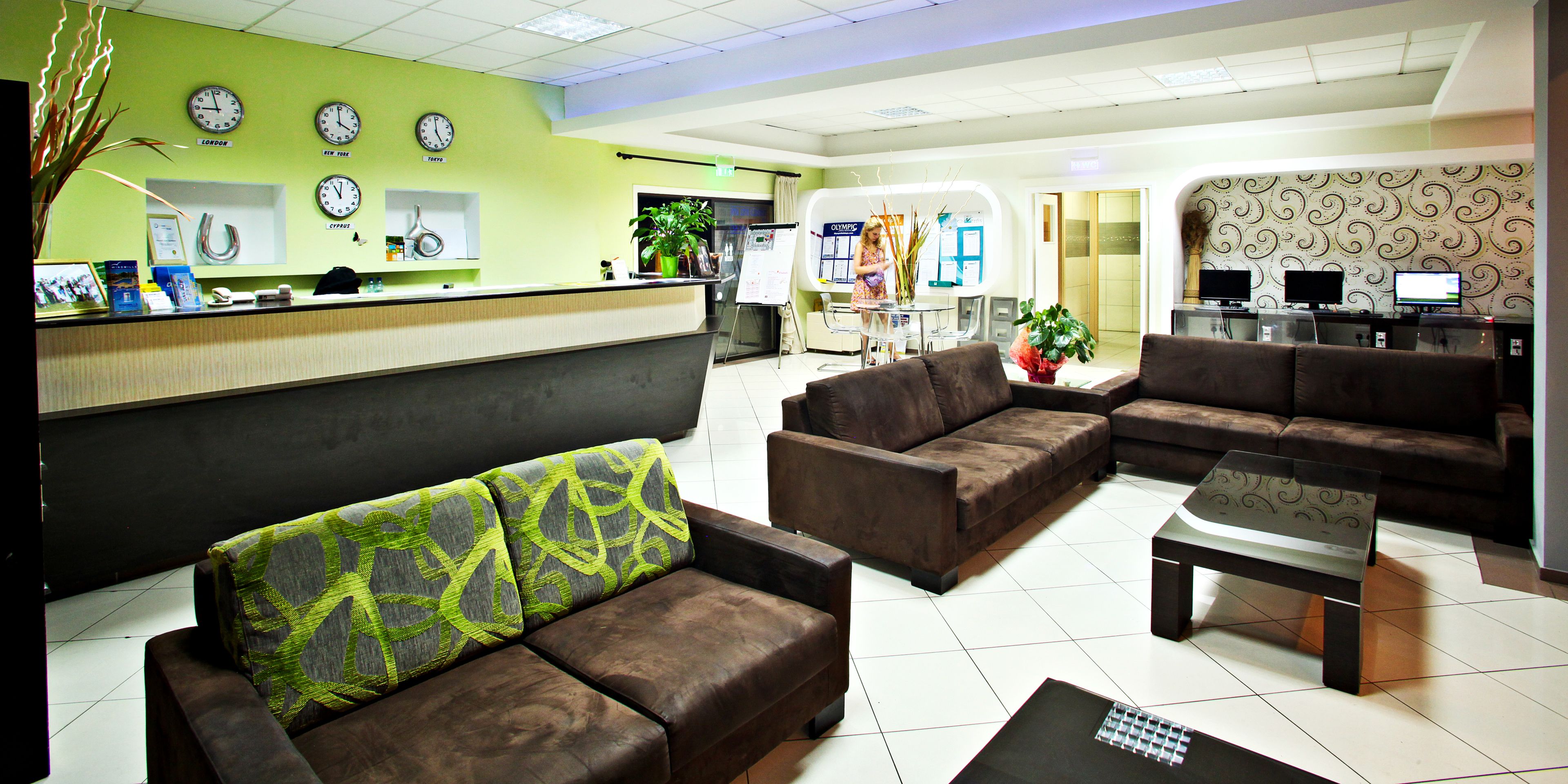 En hotellobby med en receptionsdisk, en sittgrupp och en datorarbetsplats.